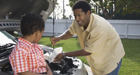 a man and his son checking the oil level on his car