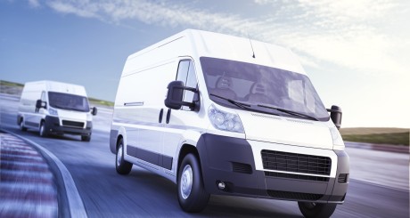 two commercial vans driving down the highway