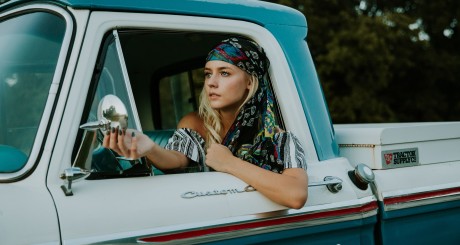 a blonde woman driving an older blue and white pickup truck