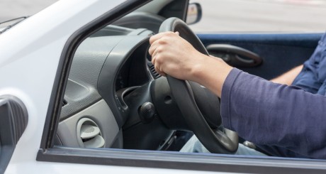 two hands on a vehicle steering wheel