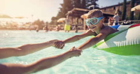 Un niño joven con gafas flota en un juguete inflable para la piscina.