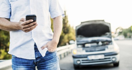 man standing in front of broken down car