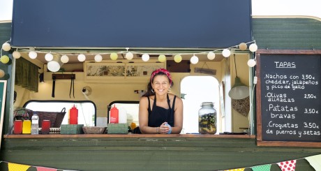 a taco truck owner smiling and looking out from her taco truck