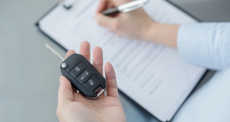 holding keys and filling out rental car form