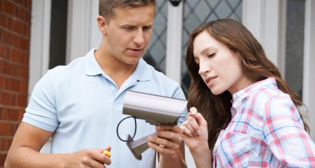 a man and a woman looking at a security camera before installing it at their home