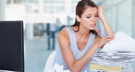 a stressed woman looking through a stack of papers