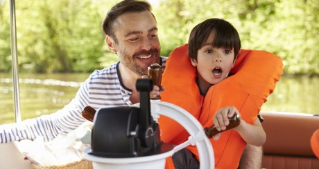 a father and his child safely operating a boat on the water