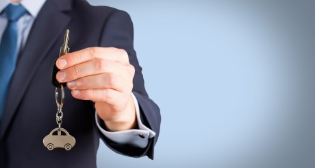 a man in a suit with a set of car keys dangling in his hand