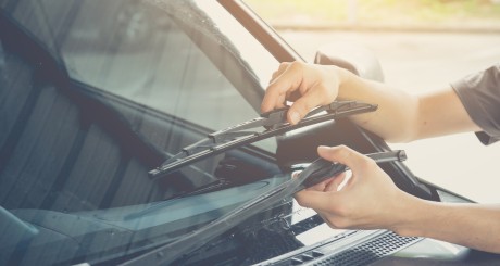 a driver installing new windshield wiper blades on their car