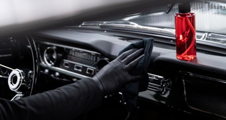 an auto detailer cleaning the dashboard of a vehicle