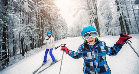 A boy skiing downhill with his friend