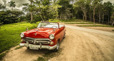 classic car driving down dirt road