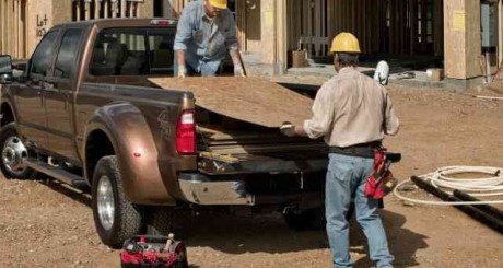 two contractors unloading plywood from the bed of their truck