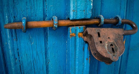 un candado oxidado en una puerta azul