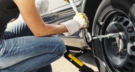 a woman changing her car tire on the side of the road