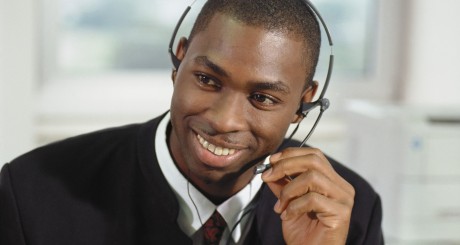 a smiling customer service agent speaking to a customer over a headset