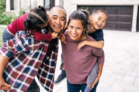 family of four standing outside their home