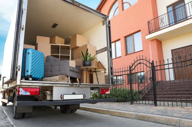 a moving truck filled with boxes and furniture outside of an apartment building