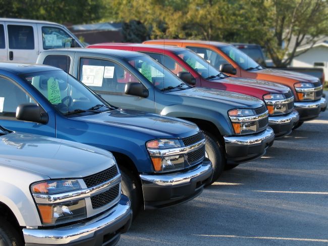 a row of five used pickup trucks of a variety of colors for sale