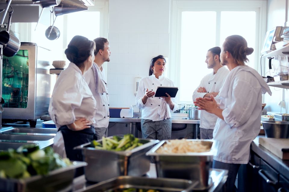 a catering team meets in a kitchen to plan their upcoming event