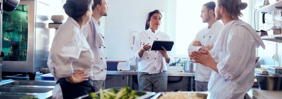 a catering team meets in a kitchen to plan their upcoming event